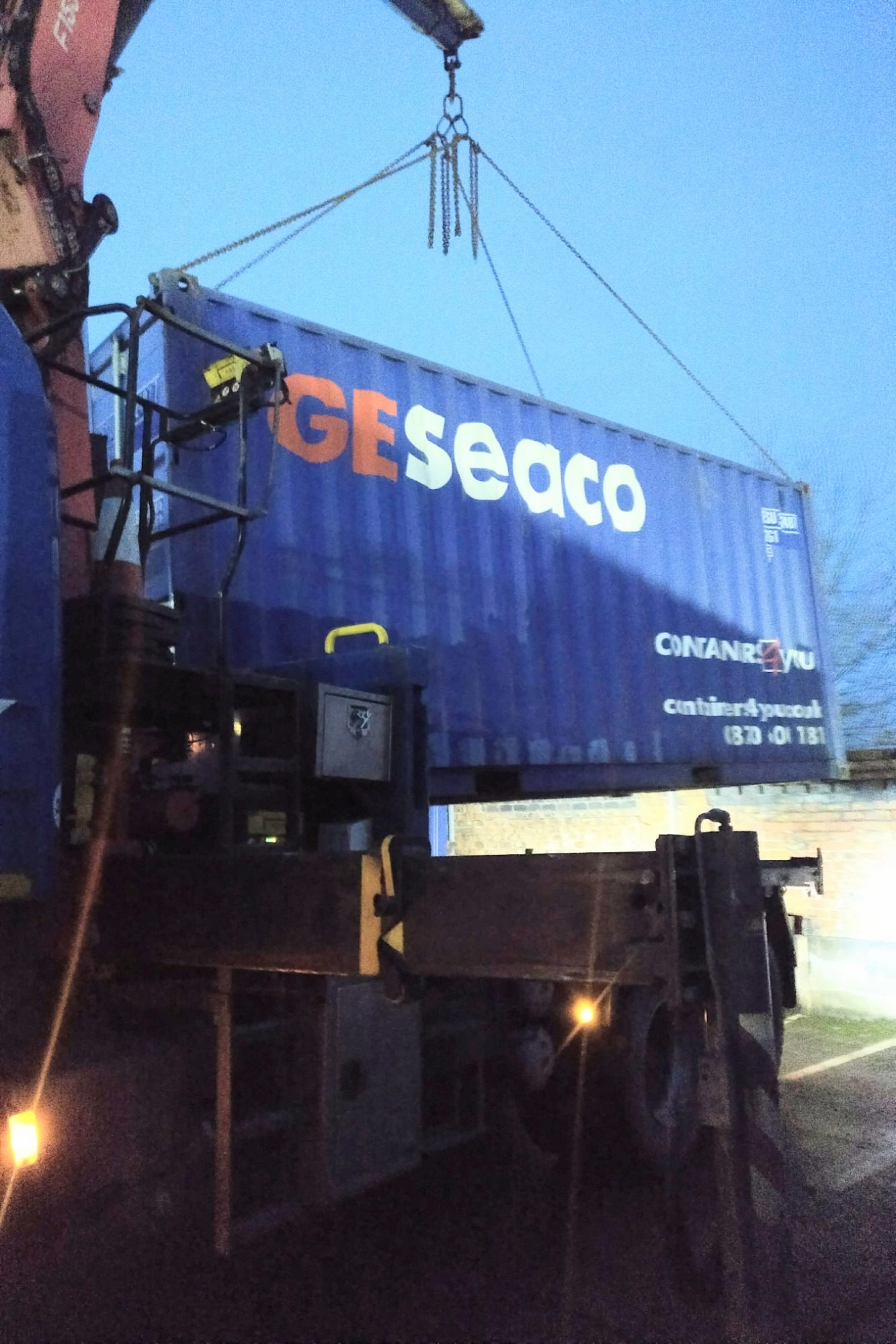 heavy plant and equipment lifting a shipping container on a commercial yard