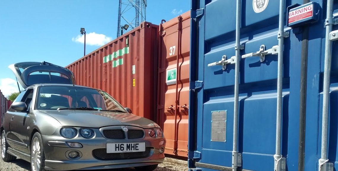 a car with its boot open about to unload items into a shipping container