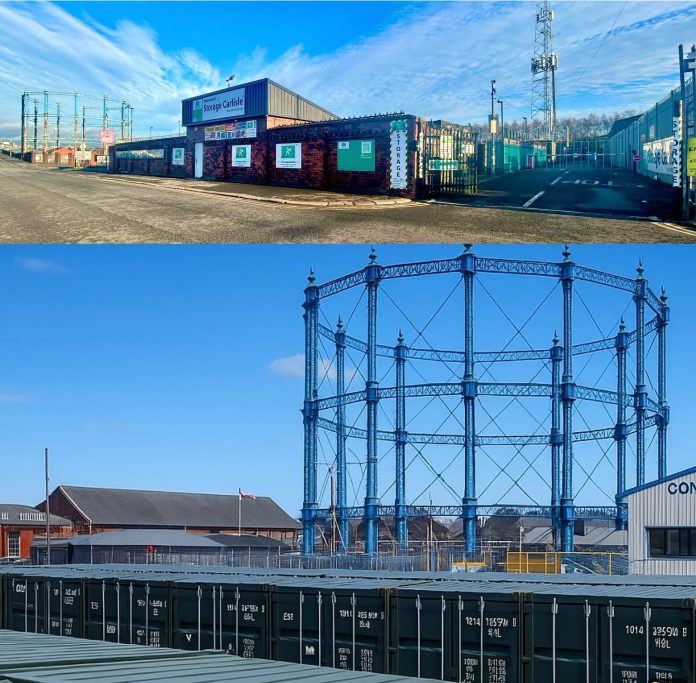 Industrial site featuring shipping containers and a gas holder structure against a clear sky.