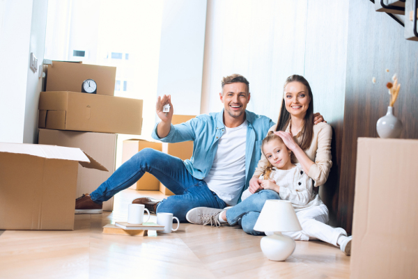 a happy family moving into their home sat beside boxes