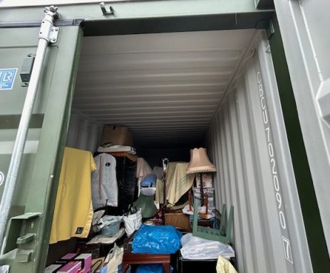 Interior of a shipping container filled with various household items and clothing.