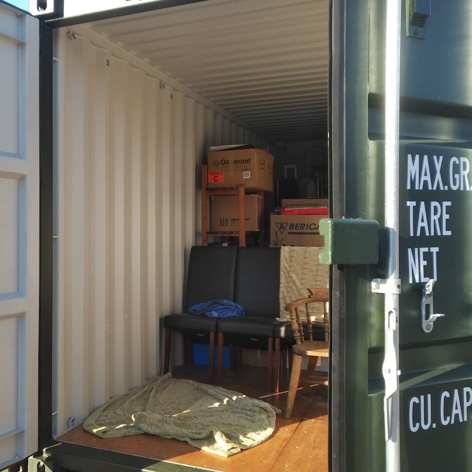 Interior of a shipping container filled with stacked boxes and furniture.