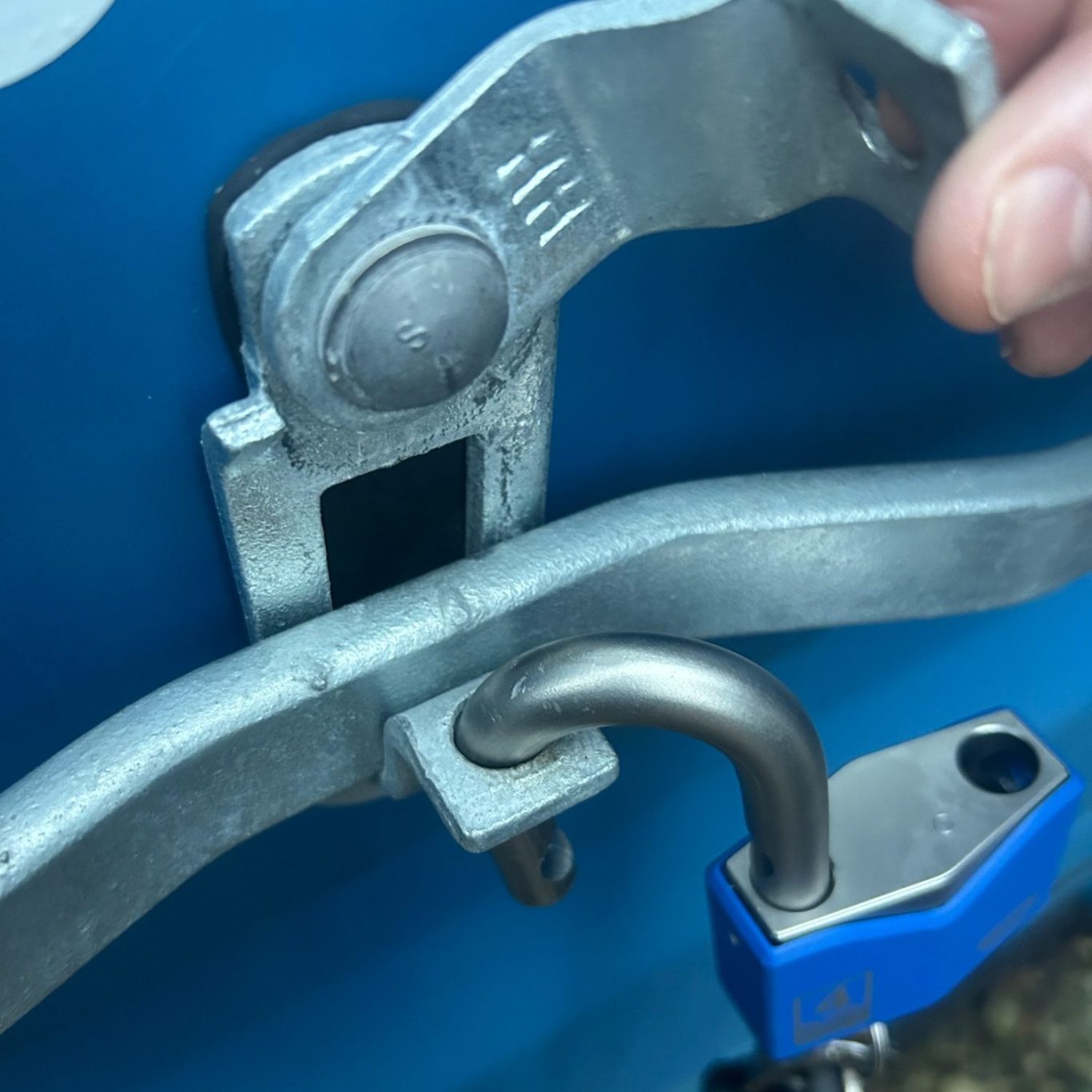 Close-up of metal latch being secured with a strong padlock on a blue shipping container.