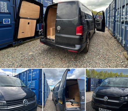 Volkswagen van parked among shipping containers on a self storage facility, with open rear doors revealing interior.